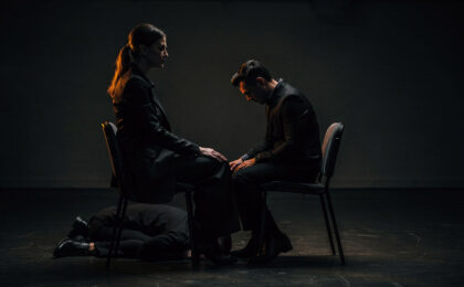 Domina sitzt im Schatten und blickt auf einen knieenden Mann, verborgene Rollen eines devoten Mannes